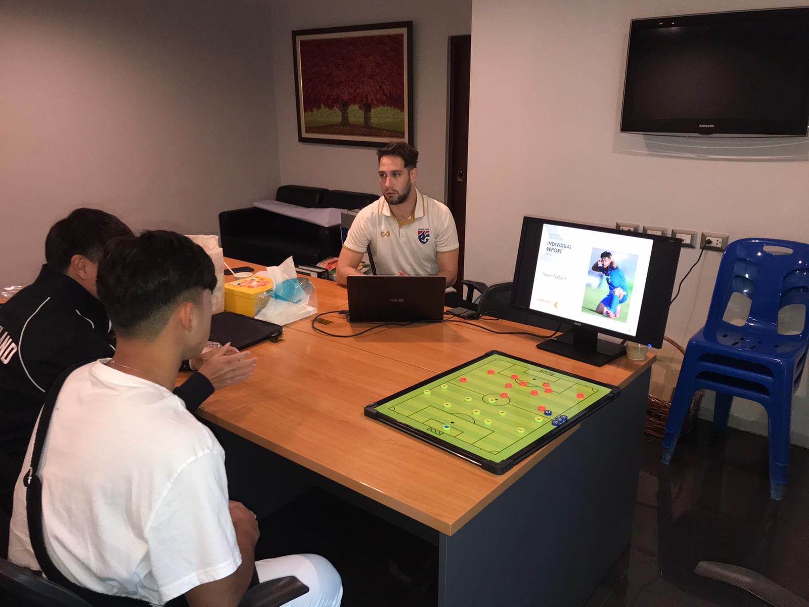 Pau Garnatje Font presenting an individual report to a player at a table, tactics board in front of them